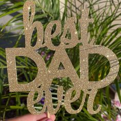 a person holding up a cake topper that says best dad ever