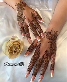 two hands with henna designs on them next to a white rose and a flower