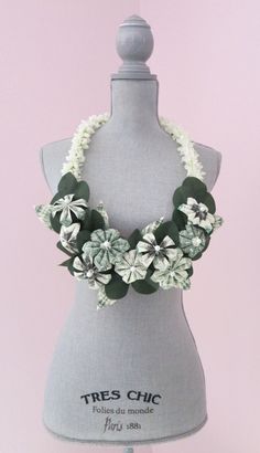 a mannequin with white flowers and green leaves on it's neckline