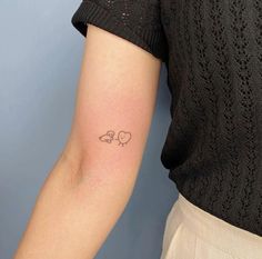 a woman's arm with a small tattoo of two birds on the left side of her arm