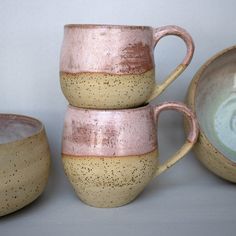 three cups and two bowls sitting next to each other