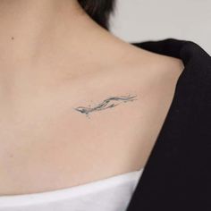 a woman's shoulder with a small wave tattoo on it