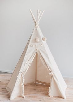 a teepee with white trim and tassels on the top is sitting on a wooden floor