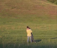 two people are standing in the grass with their arms around each other