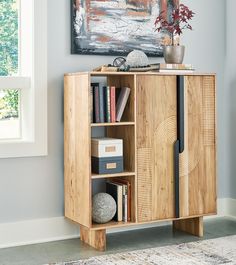 a wooden cabinet with books and magazines on it next to a painting in a room