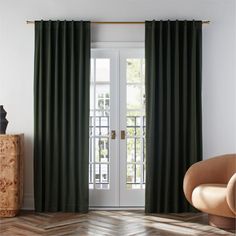 a living room with green curtains and a chair in front of the door that is open