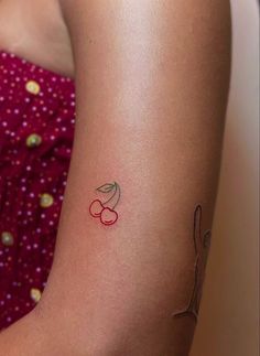 a small tattoo on the arm of a woman's left arm with cherries