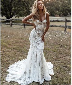 a woman in a wedding dress standing on the grass with her hand on her hip