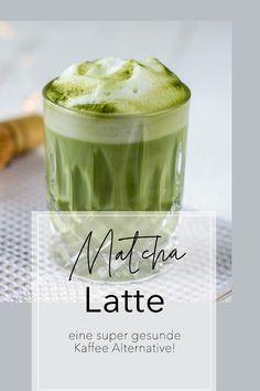 matcha latte in a glass on a table with the words matcha latte above it