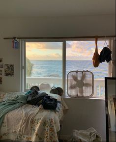 an unmade bed sitting in front of a window next to a wall with pictures on it