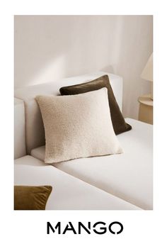 a white couch with two pillows on it and the words mango written in black below