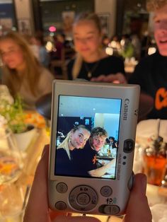 a person holding up a cell phone to take a selfie with two other people in the background