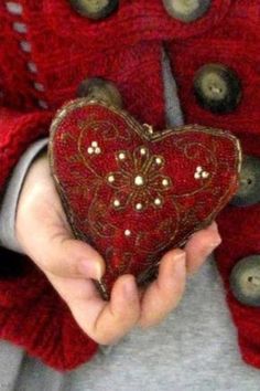 someone is holding a heart shaped object in their hands with buttons on the back of it