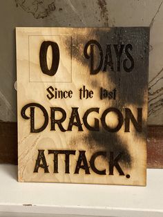 a wooden sign that says, 0 days since the dragon attack is on it's side