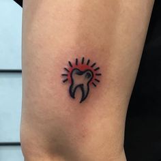 a small tooth tattoo on the thigh