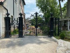 an iron gate is in front of a white house with black wrought iron gates on both sides