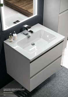 a white sink sitting under a mirror in a bathroom next to a wall mounted faucet