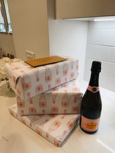 a bottle of wine sitting next to two wrapped presents on a countertop in a kitchen