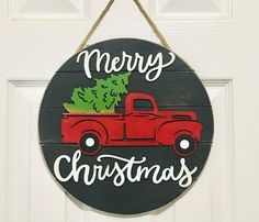 a christmas ornament hanging on a door with a red truck carrying a tree