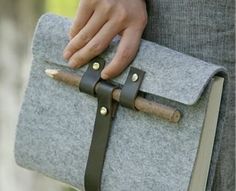 a woman holding a gray and brown bag with leather straps on it's side