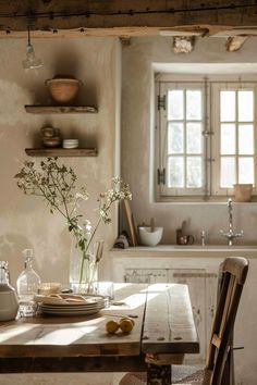 a wooden table topped with a vase filled with flowers next to a kitchen sink and window