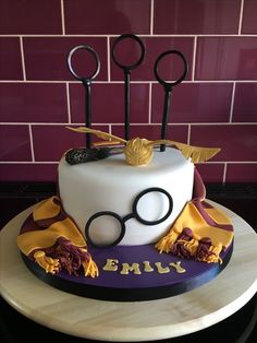 a harry potter themed birthday cake with glasses and wands on the top is purple and gold