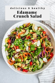 a white bowl filled with salad next to a striped towel and napkin on the side