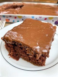 a piece of chocolate cake on a white plate with a fork next to the slice