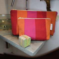 two orange and pink bags sitting on top of a counter next to a green box