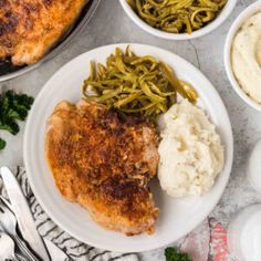 chicken, mashed potatoes and green beans on a white plate with silverware next to it