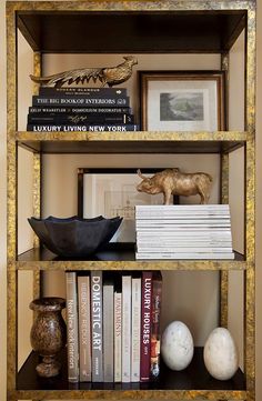 a bookshelf filled with lots of books next to a vase and other items