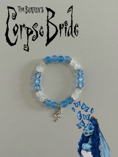 a bracelet with blue glass beads and a fairy tale character charm on it, sitting in front of a white background