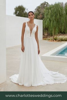 a woman standing in front of a pool wearing a wedding dress with an open back