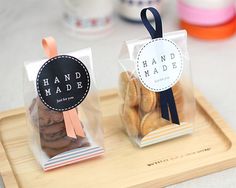 two clear bags filled with cookies on top of a wooden tray