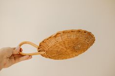 a person holding a wicker basket in the air with one hand and another hand reaching for it