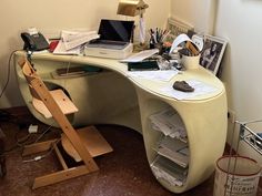 a desk with a laptop computer on top of it next to a chair and other office supplies