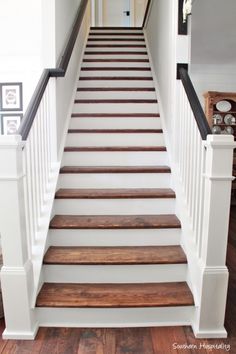 a set of wooden stairs leading up to a second floor with white railings and wood handrails