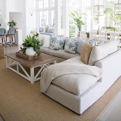 a living room filled with lots of furniture and plants on top of a wooden table