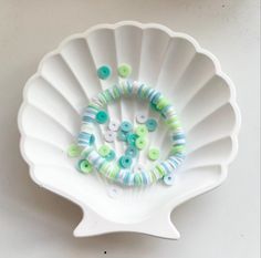 a white bowl with green and blue beads on it