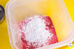 a plastic container filled with powdered sugar next to a measuring cup on a yellow surface