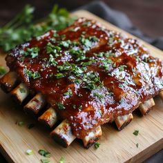 a wooden cutting board topped with ribs covered in bbq sauce and garnished with parsley