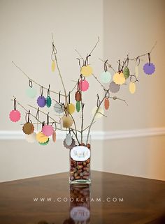 a vase filled with lots of different colored paper balls on top of a wooden table