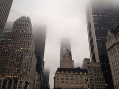 the city skyline is covered in fog and low clouds