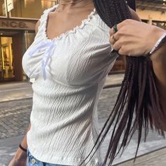 a woman with long braids is standing on the street and holding onto her hair