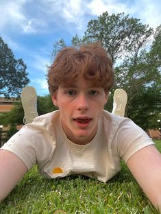 a boy laying in the grass with his hands on his hips looking at the camera