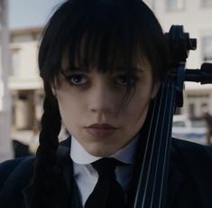 a woman wearing a suit and tie holding a violin