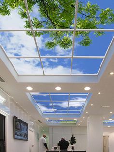 two men are standing in the middle of a room with skylights on the ceiling