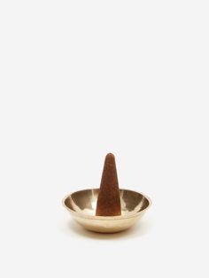 a small metal bowl with a brown cone on the top in front of a white background