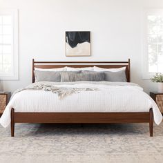 a bed with white sheets and pillows in a room