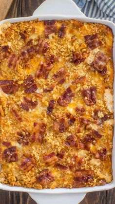 a casserole dish filled with bacon and cheese on top of a wooden table